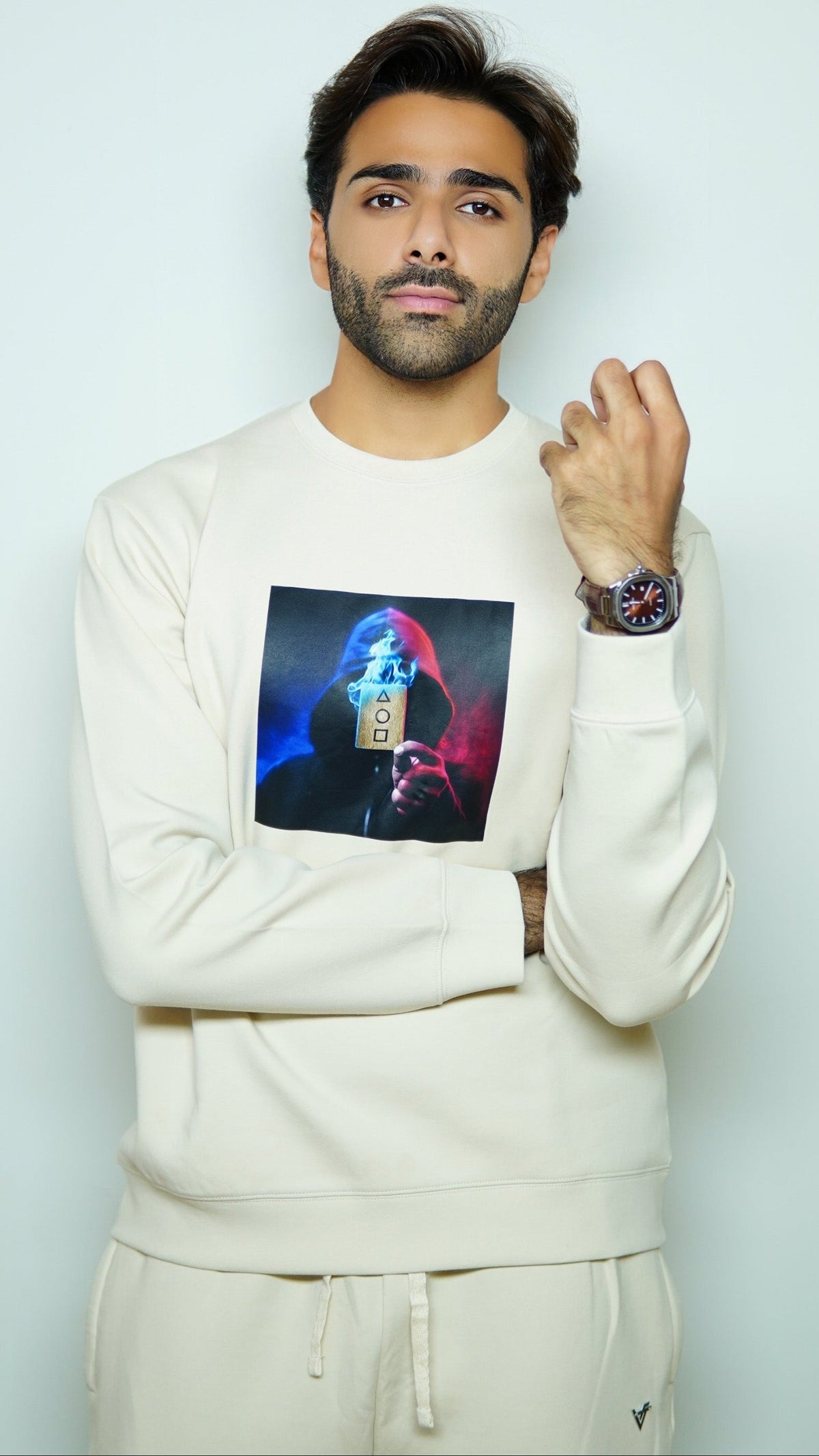 Man wearing a white sweatshirt with a colorful graphic design on a light gray background