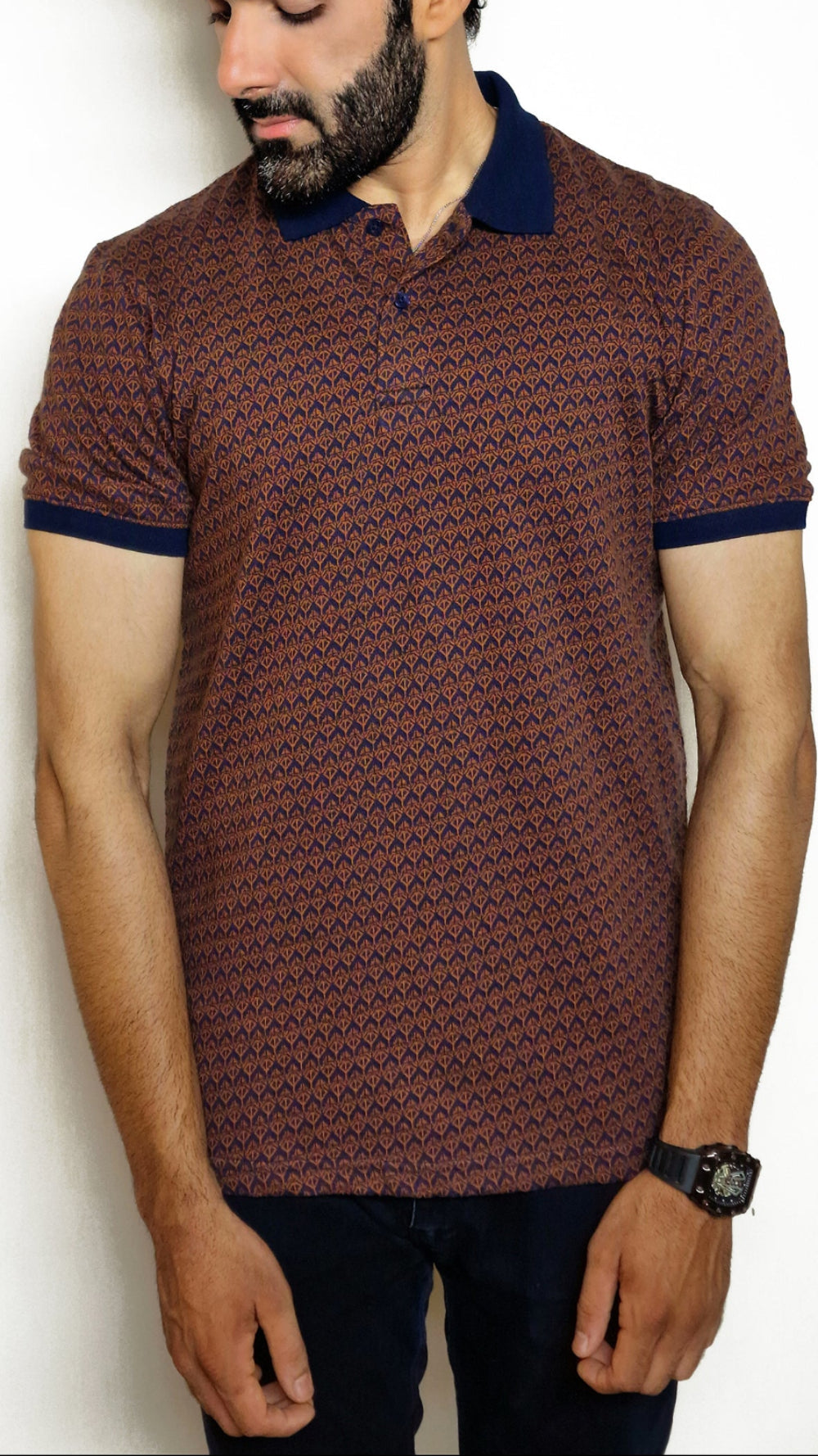 A man wearing a navy and light brown geometric patterned polo shirt with a collar.