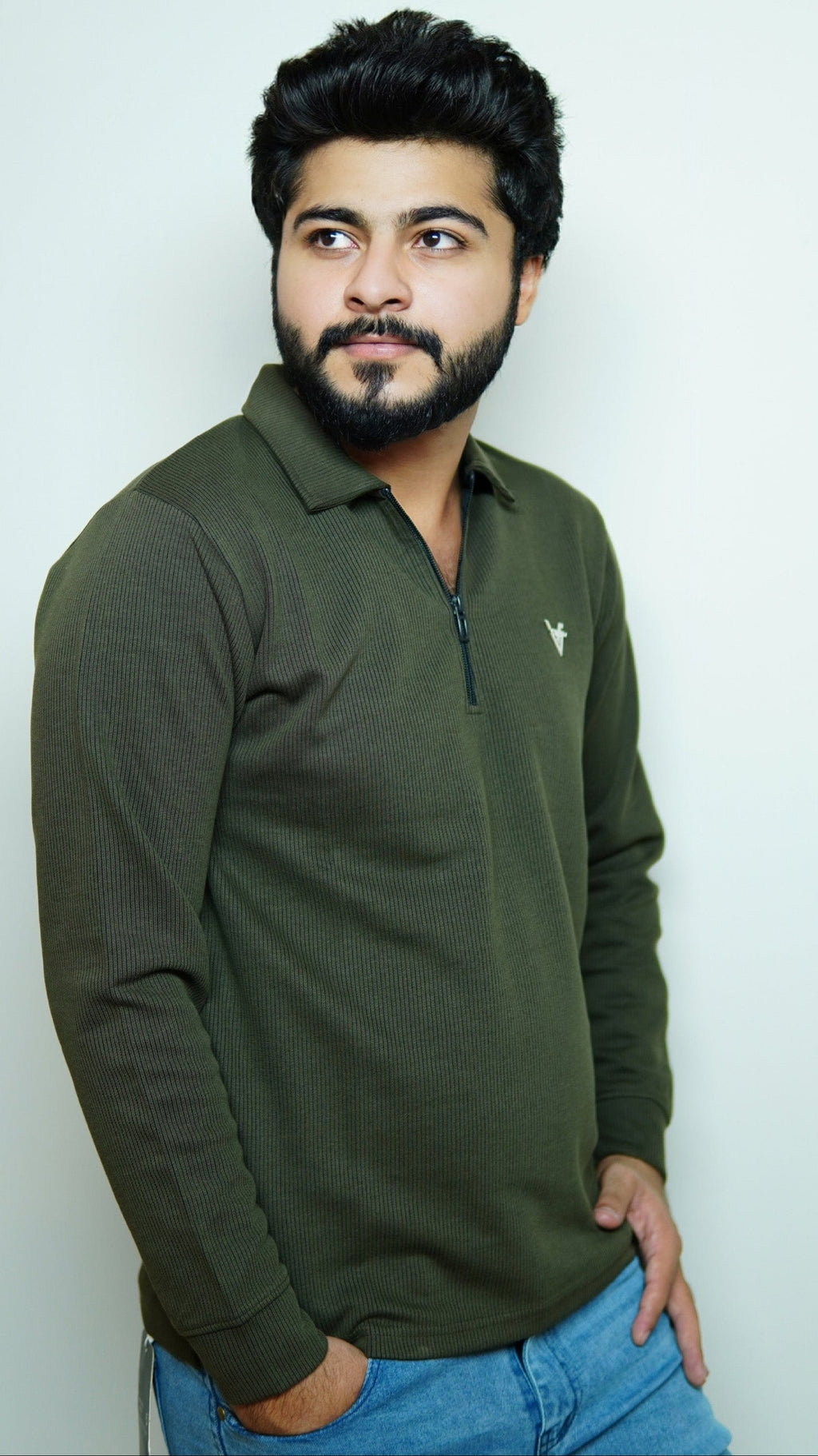 Man wearing a green long-sleeve shirt and blue jeans against a white background