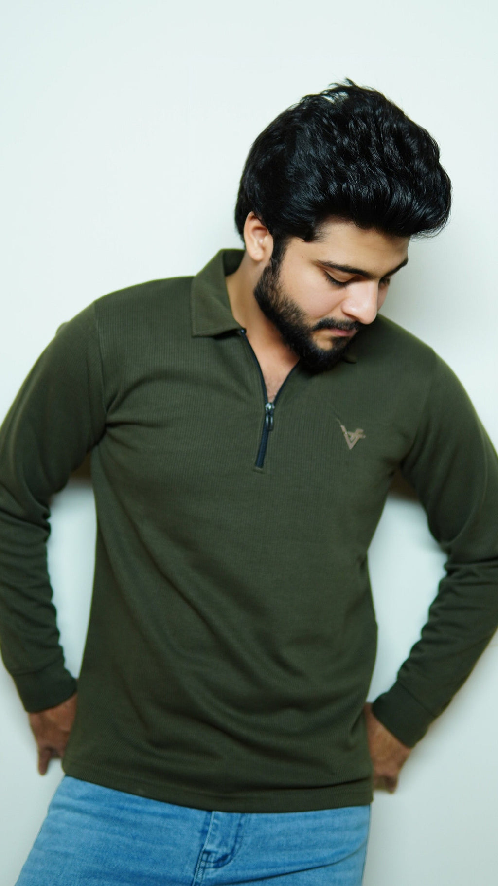 Man wearing a green long-sleeve shirt with a small logo against a white background
