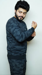 Man wearing a dark camouflage outfit against a white background